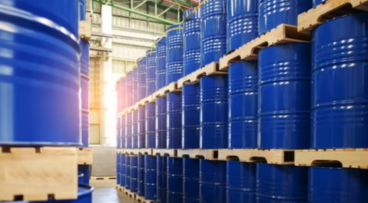 Stacked blue industrial barrels storing petrochemical materials in a warehouse for pharma and manufacturing supply chains