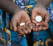Person holding essential medicines in hands including tablets for HIV and malaria treatment in developing countries