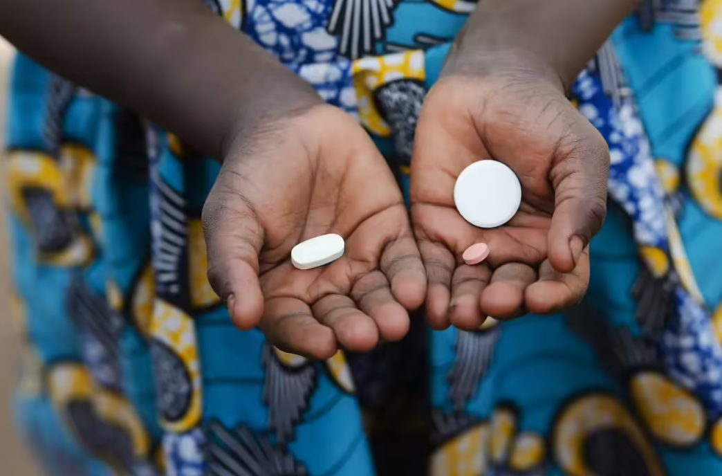 Person holding essential medicines in hands including tablets for HIV and malaria treatment in developing countries
