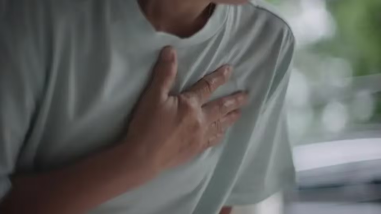 Man experiencing chest pain holding chest, possible heart attack symptoms in adult male