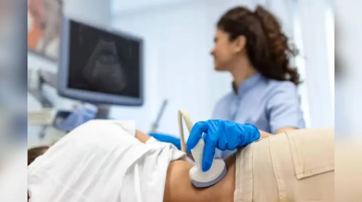 Doctor performing ultrasound scan on patient abdomen using medical imaging device