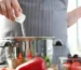 Adding salt while cooking in kitchen highlighting high sodium diet and heart health risks