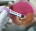 Gloved hand holding an Ebola virus blood test sample tube during laboratory testing